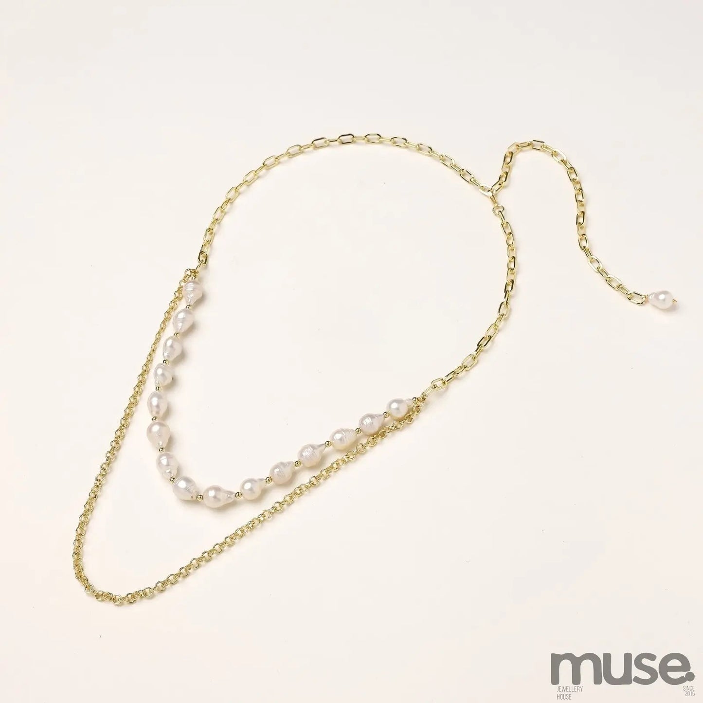 Layered gold chain necklace with irregular freshwater pearls on cream background, showing adjustable dual-strand design.