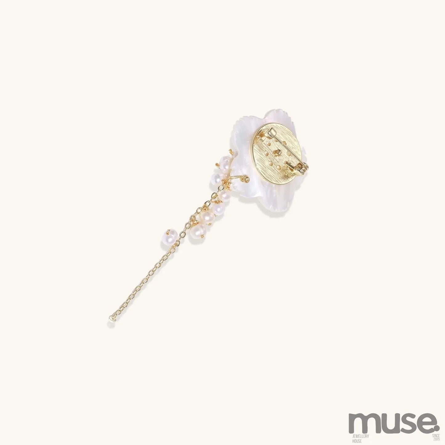 Delicate hair pin featuring translucent shell flower with cascading freshwater pearls on gold chain against cream background.