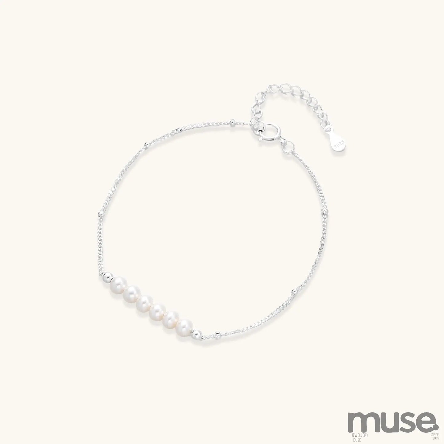 Dainty sterling silver bracelet with small white baroque pearls and adjustable chain on neutral background.