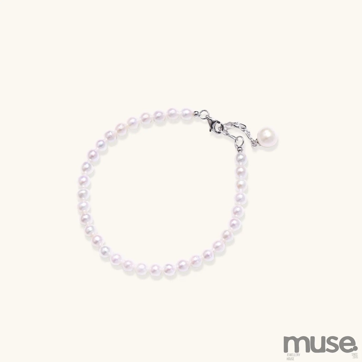Delicate sterling silver bracelet with small freshwater pearls and adjustable chain on neutral background.