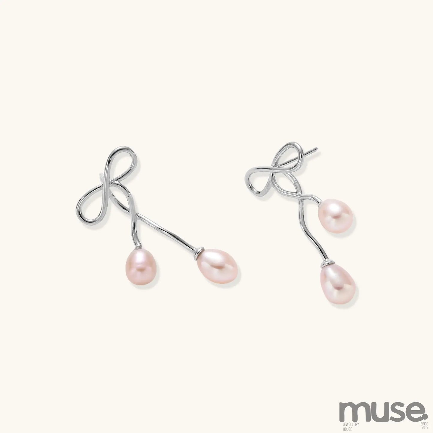 Delicate sterling silver wire earrings with organic bow shapes and two pink freshwater pearls on white background