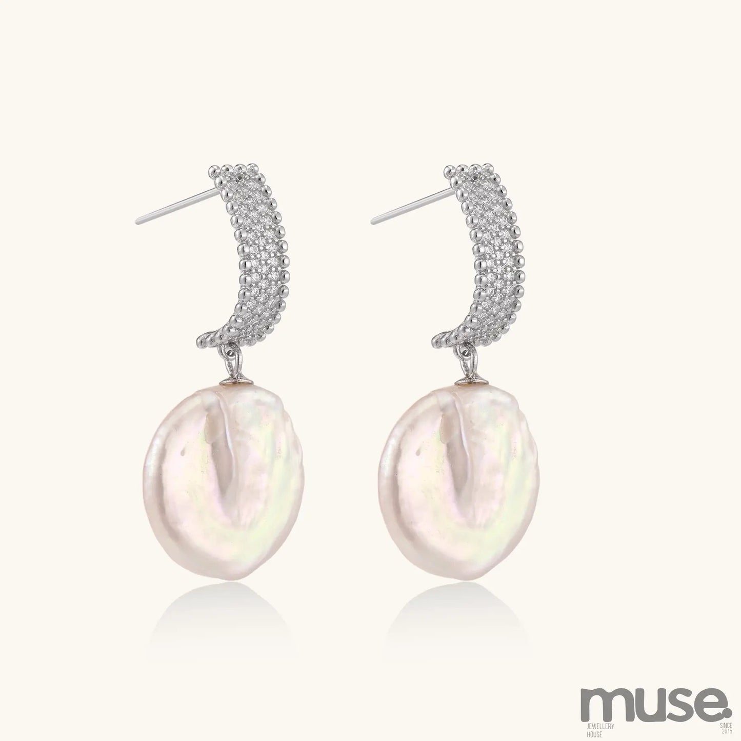 Sterling silver huggie earrings with lustrous baroque pearls displaying iridescent pink and cream tones on white background.