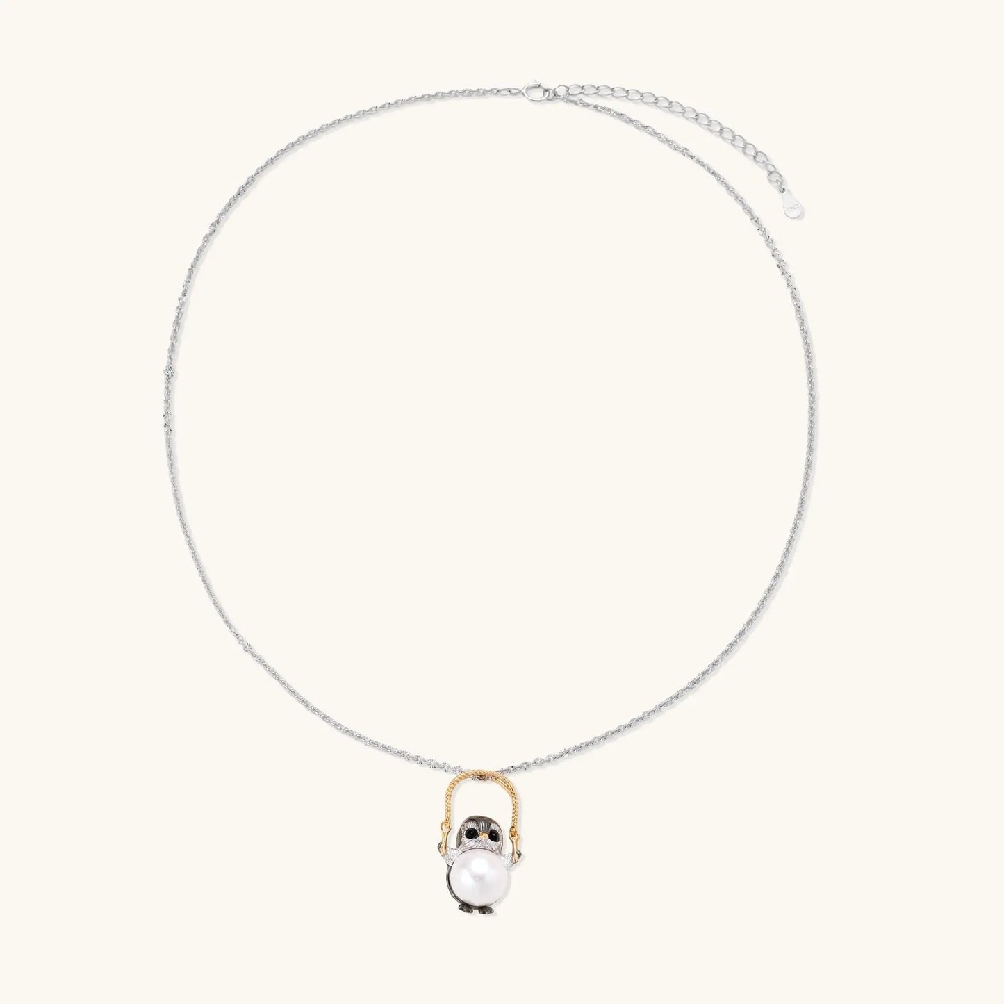 Silver owl pendant holding a round freshwater pearl on an adjustable chain against white background