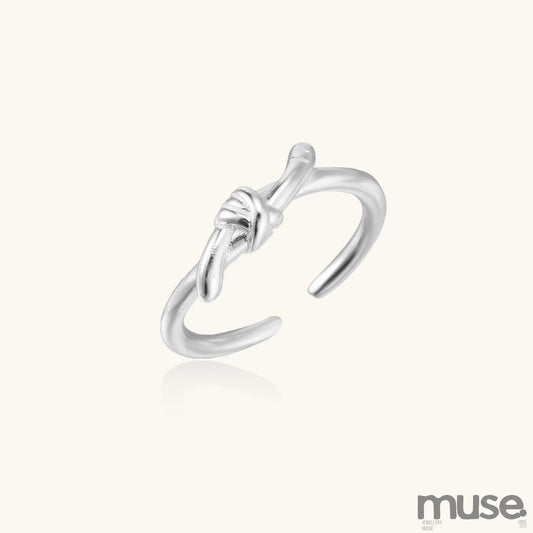 Delicate sterling silver ring with geometric knot design on white background, showcasing adjustable open band.
