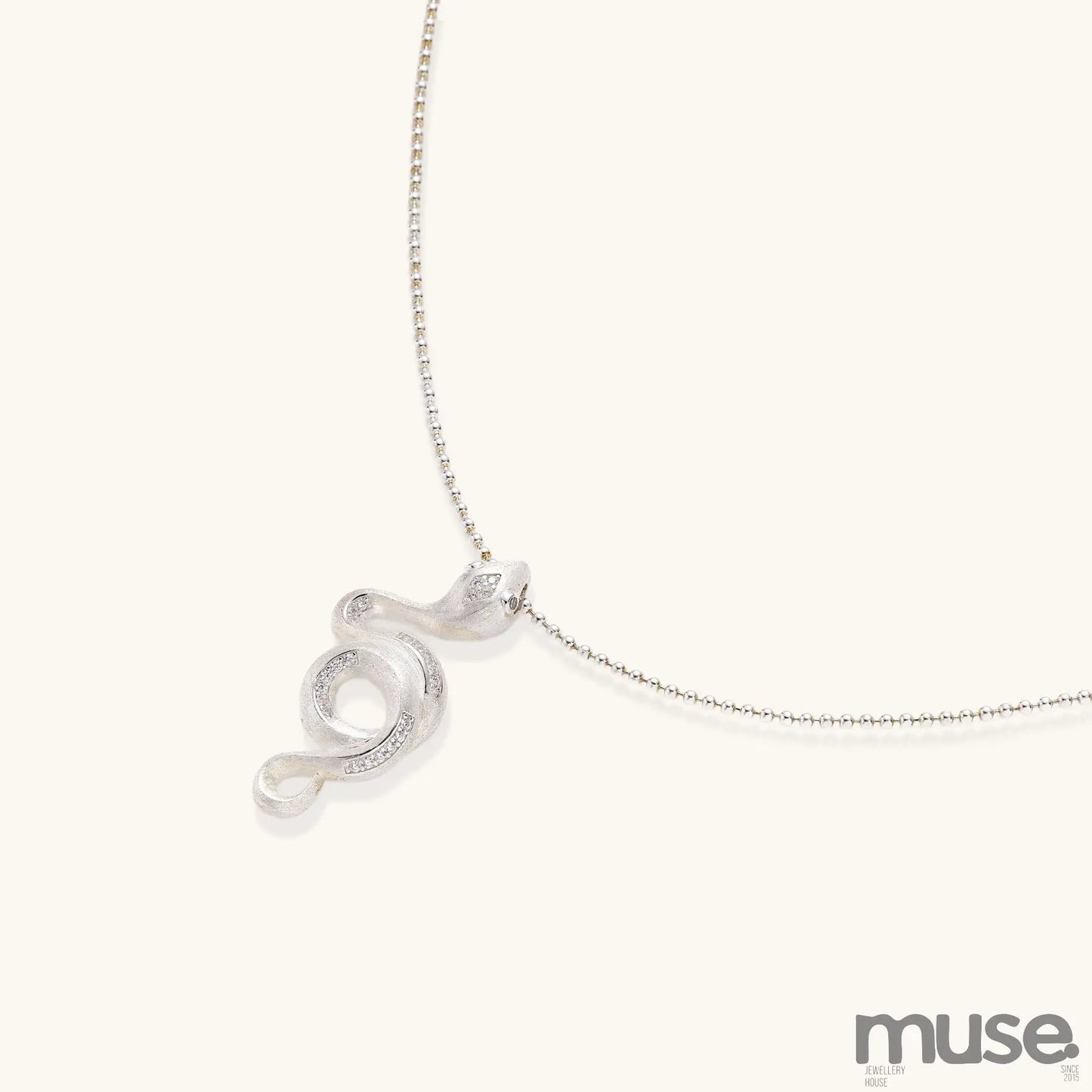 Sterling silver snake pendant necklace with zirconia crystals on adjustable chain against cream background