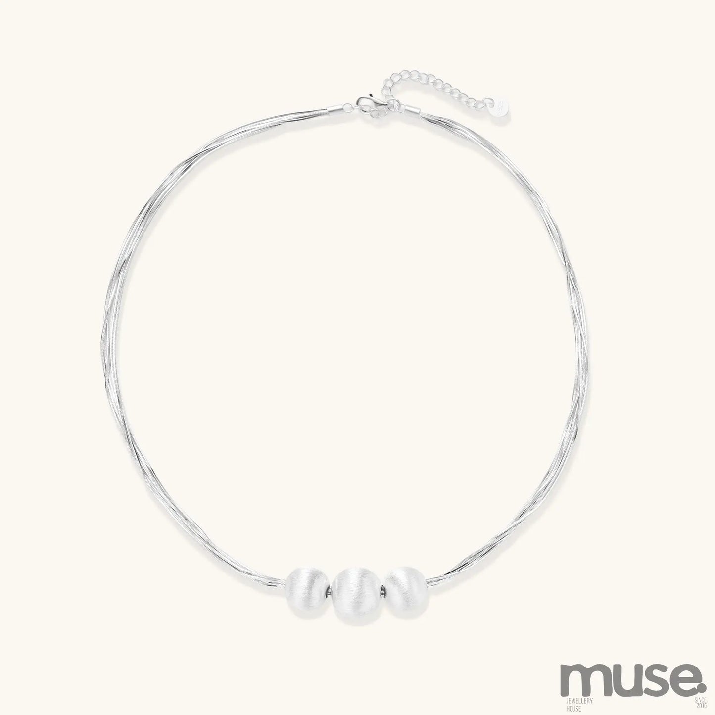 Multi-strand sterling silver necklace with three polished round beads clustered at center on white background.