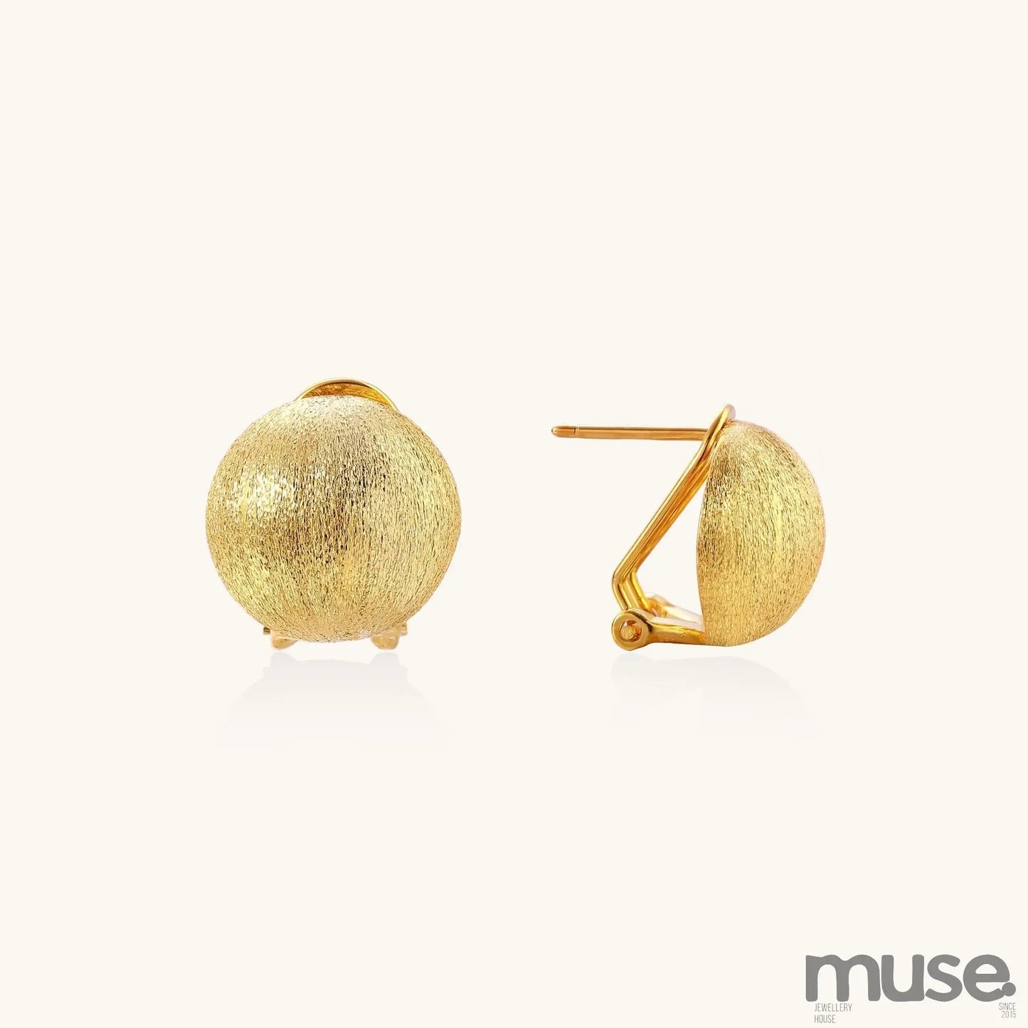 Close-up of textured gold-plated sterling silver dome clip-on earrings with brushed finish on white background.