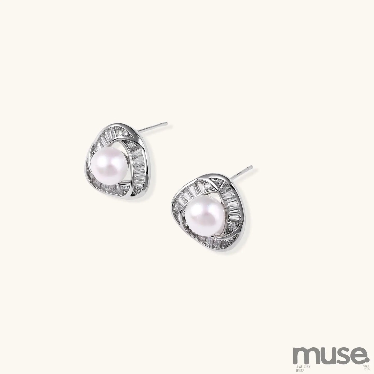 Close-up of triangular gold-plated stud earrings with central freshwater pearl surrounded by baguette crystals