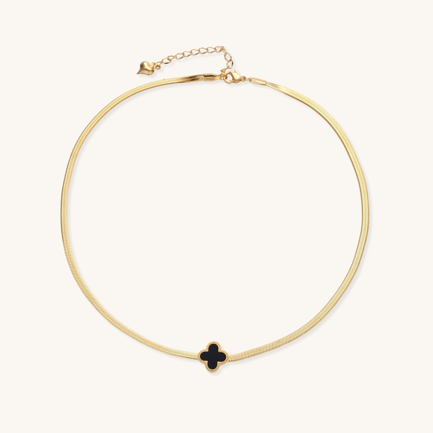 Delicate gold-plated chain necklace featuring a black quatrefoil clover pendant on white background.