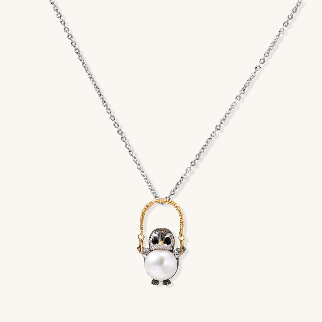 Silver owl pendant holding a round freshwater pearl on an adjustable chain against white background