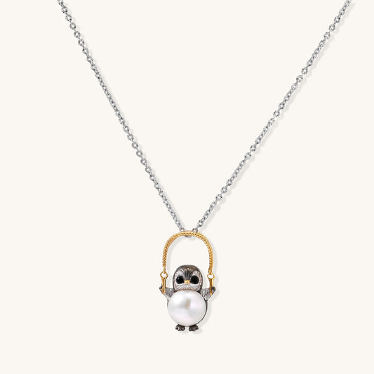 Silver owl pendant holding a round freshwater pearl on an adjustable chain against white background