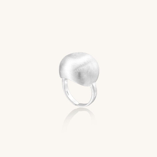 Minimalist sterling silver ring with large brushed disc top and adjustable band on white background.