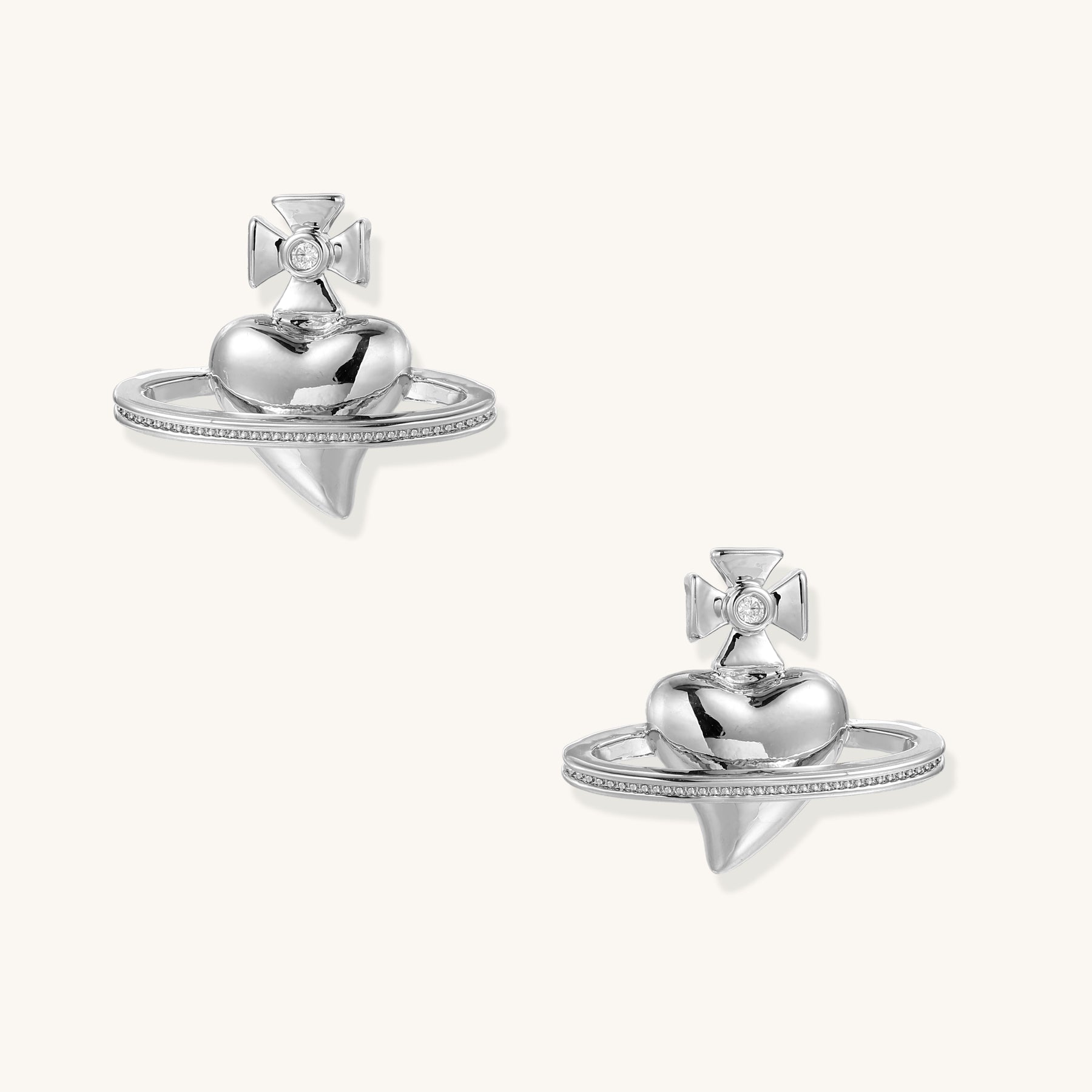 Close-up of UFO-shaped gold-plated stud earrings with zirconia crystals and cross details on white background.