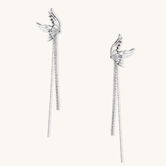Gold-plated angel wing earrings with long cascading crystal chains on neutral background, showing intricate feather details