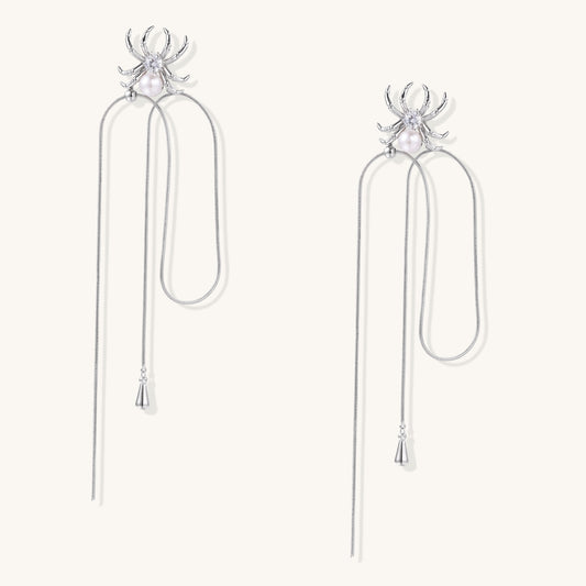 Two elegant gold-plated spider drop earrings with white pearls and long chain details on white background.