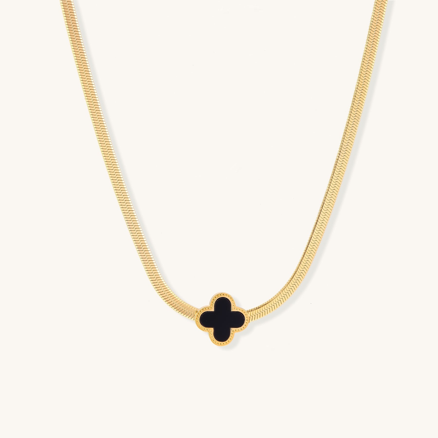 Delicate gold-plated chain necklace featuring a black quatrefoil clover pendant on white background.