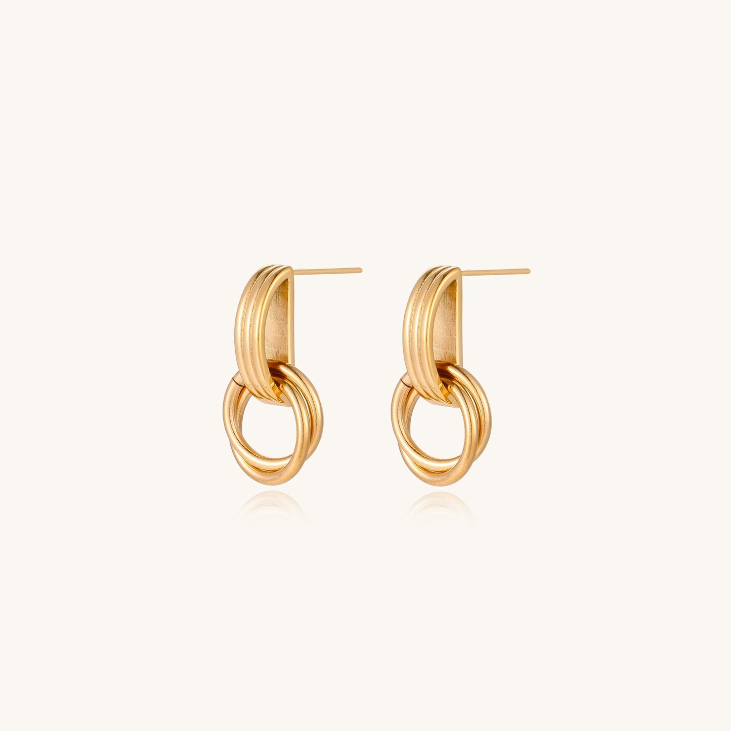 Geometric gold earrings with ribbed linear top section and circular drop elements on white background.