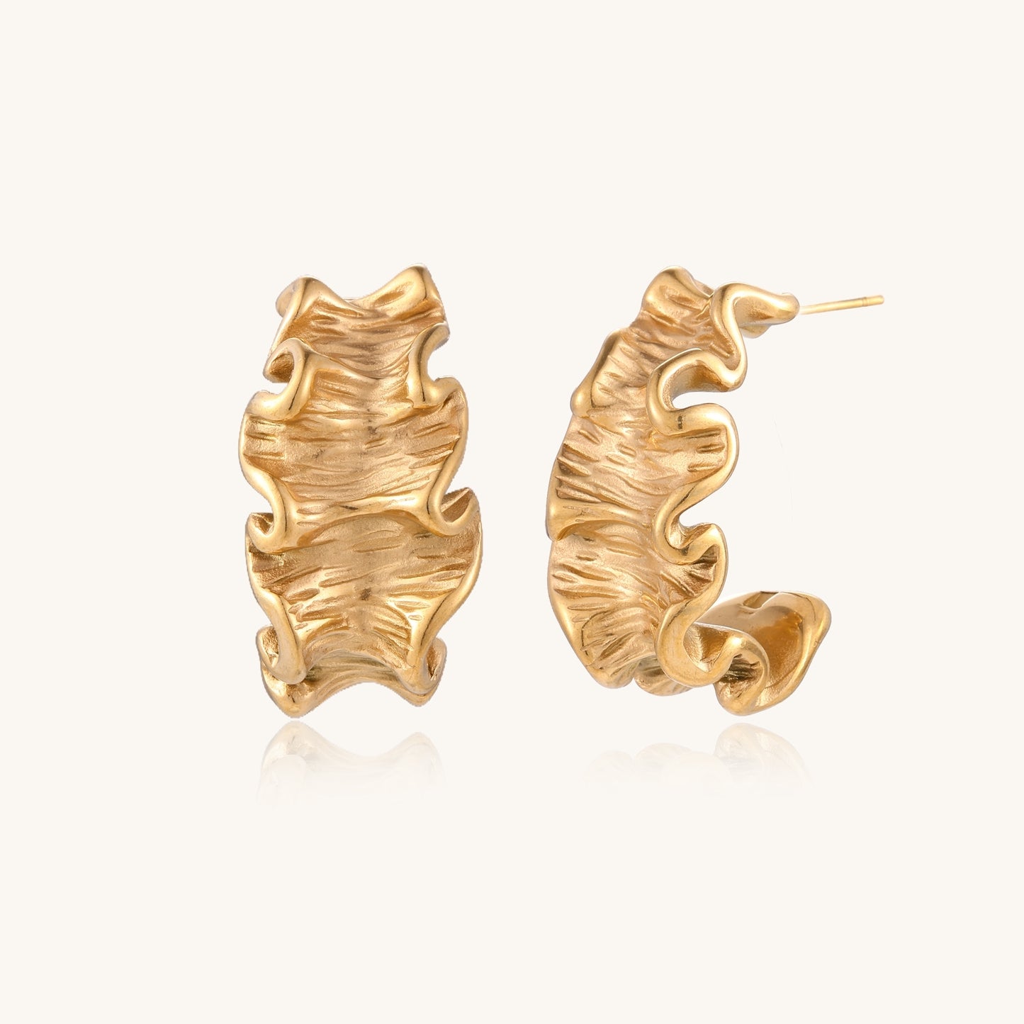 Textured gold-plated hoop earrings with wavy sculptural ridges displayed against a neutral background.